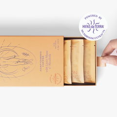 Slightly opened box of Flow Lion's Mane and Rhodiola adaptogenic coffee showing three single serve sachets. A hand pull the box open. In the top right corner is a sticker that reads: Powered by Hifas da Terra mushroom extracts.