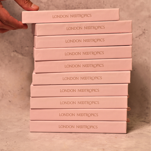 Stack of pink London Nootropics coffee boxes on a grey backdrop.