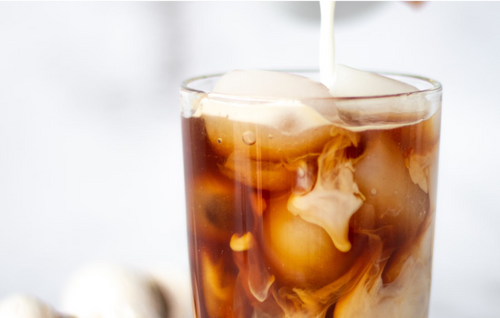 Pouring milk into iced mushroom nootropic coffee