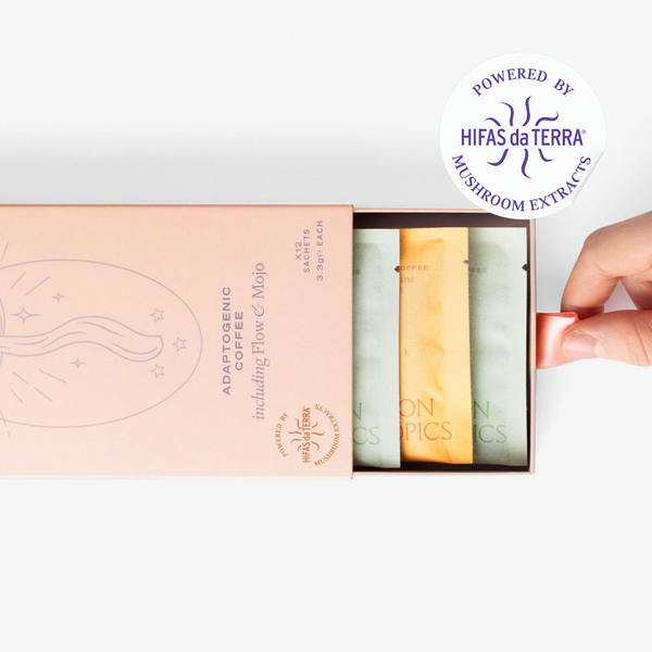 Slightly opened adaptogenic coffee selection box showing three single serve sachets: Two Mojo and one Flow. A hand pull the box open. In the top right corner is a sticker that reads: Powered by Hifas da Terra mushroom extracts.