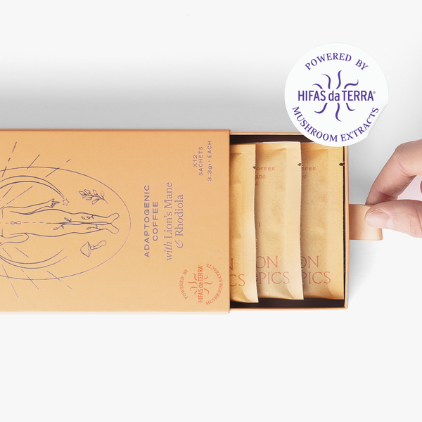 Slightly opened box of Flow Lion's Mane and Rhodiola adaptogenic coffee showing three single serve sachets. A hand pull the box open. In the top right corner is a sticker that reads: Powered by Hifas da Terra mushroom extracts.