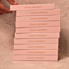 Stack of pink London Nootropics coffee boxes on a grey backdrop.