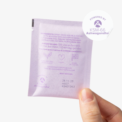 Hand holding a single-serve green sachet of London Nootropics Zen ashwagandha coffee. The backside of the sachet displays the ingredients and best before date. The image shows a sticker icon at the top right corner of the sachet that reads: Powered by KSM-66 Ashwagandha.
