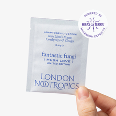 Hand holding a single-serve blue sachet of London Nootropics adaptogenic coffee with Lion's Mane, Cordyceps and Chaga. The blend featured is a Fantastic Fungi collaboration. The image shows a sticker icon at the top right corner of the sachet that reads: Powered by Hifas da Terra Mushroom Extracts.