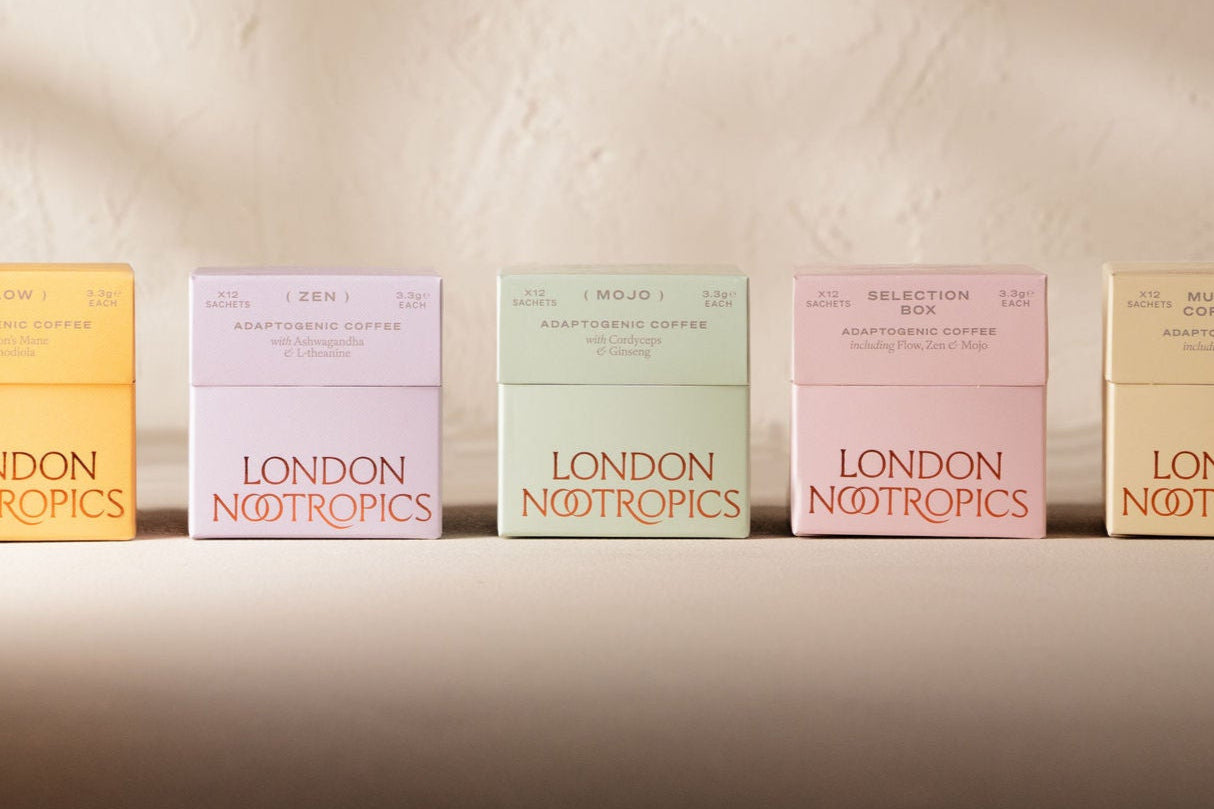 12 Sachet boxes of London Nootropics Adaptogenic boxes. From left to right: Flow blend in an orange box, Zen blend in a purple box, Mojo blend in a mint green box, a pink selection all three blends and a yellow box featuring Flow and Mojo coffee. All boxes are closed and placed on a white backdrop.