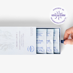 Slightly opened box of Mush Love Lion's Mane, Cordyceps, and Chaga adaptogenic coffee showing three single serve sachets. A hand pull the box open. In the top right corner is a sticker that reads: Powered by Hifas da Terra mushroom extracts.